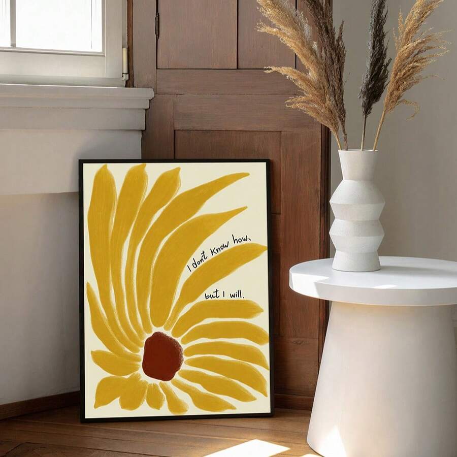 Black-framed yellow sunflower quote print beside a white table and dried grasses