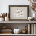 Dark-framed white pumpkin canvas print styled among books candles and seasonal gourds