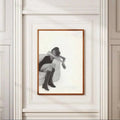 Vertical monochrome woman portrait in a slim wood frame on an ornate white wall above a herringbone floor