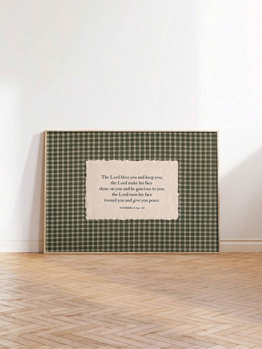 Green plaid blessing canvas artwork in a slim light frame leaning against a white wall on parquet flooring