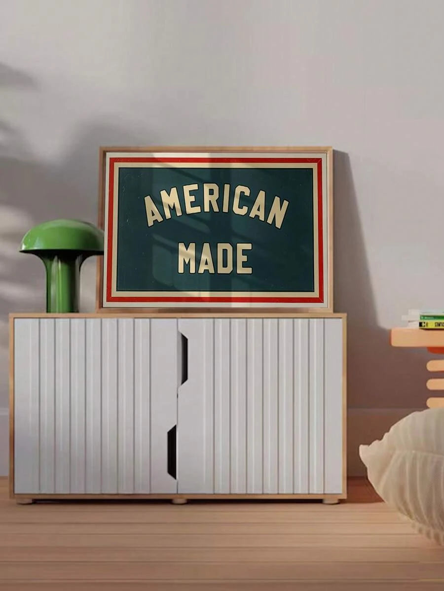 Framed AMERICAN MADE poster displayed on a fluted cabinet beside a green lamp