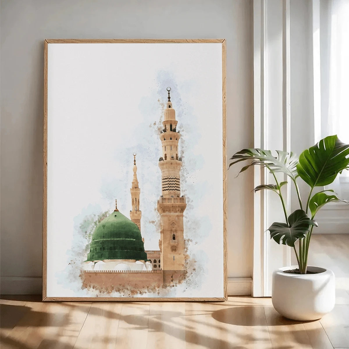 Watercolor mosque canvas art in a light wood frame beside a potted plant