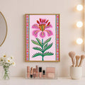 Pink floral folk-art print above a vanity with cosmetics, brushes, and daisies
