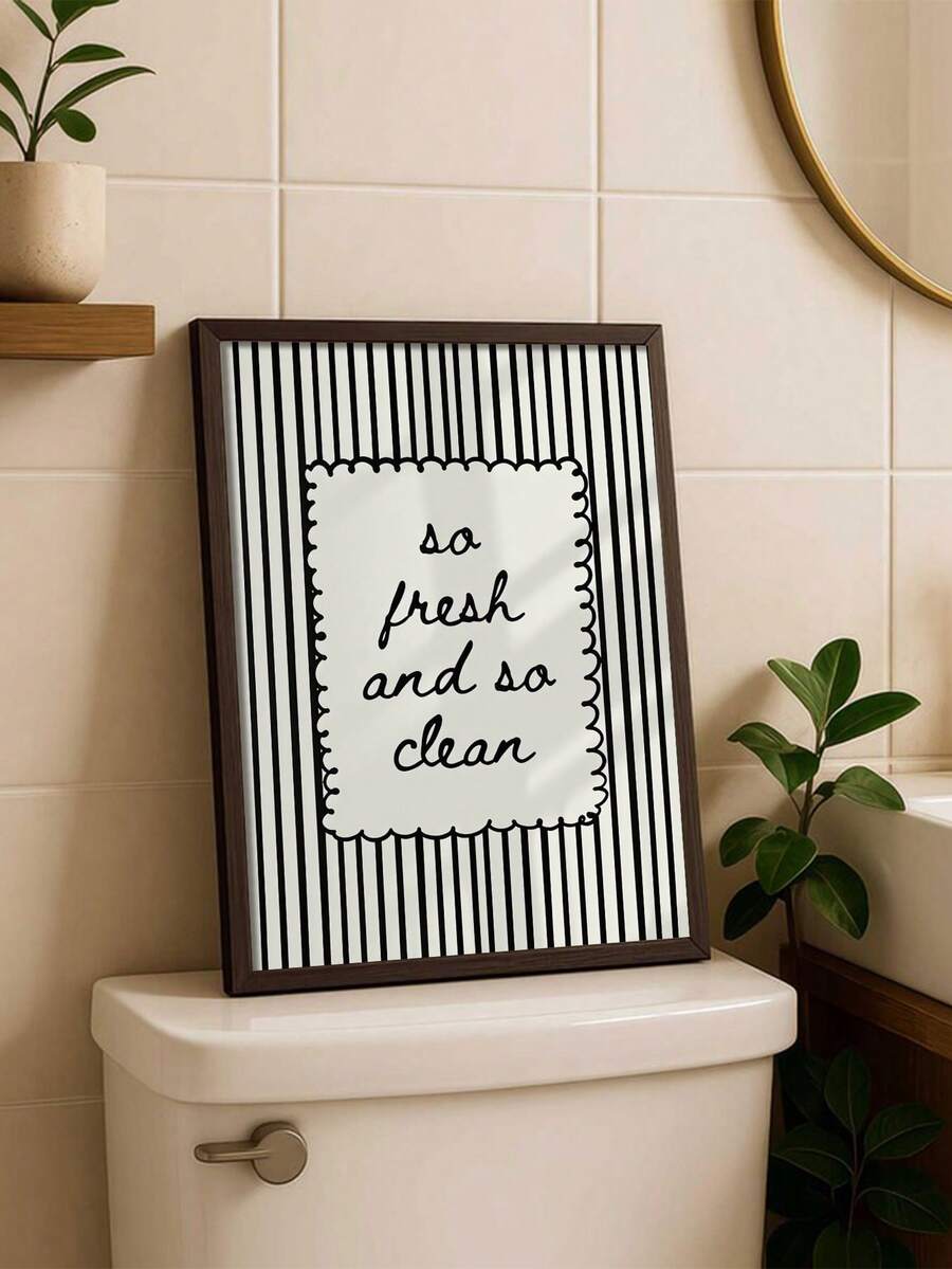 Dark-framed bathroom poster with black vertical stripes styled beside a mirror and greenery