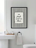 Black-framed minimalist typography canvas poster displayed in a modern white bathroom