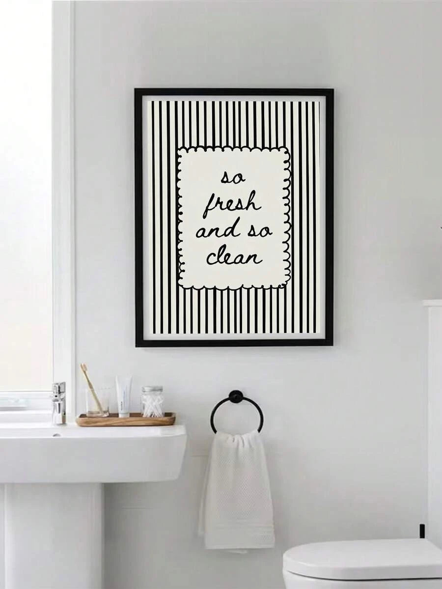 Black-framed minimalist typography canvas poster displayed in a modern white bathroom