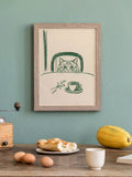 Olive-green cat breakfast artwork in a gray wood frame above a teal kitchen counter