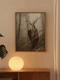 Framed antlered skull figure canvas displayed above a wooden console with a glowing lamp