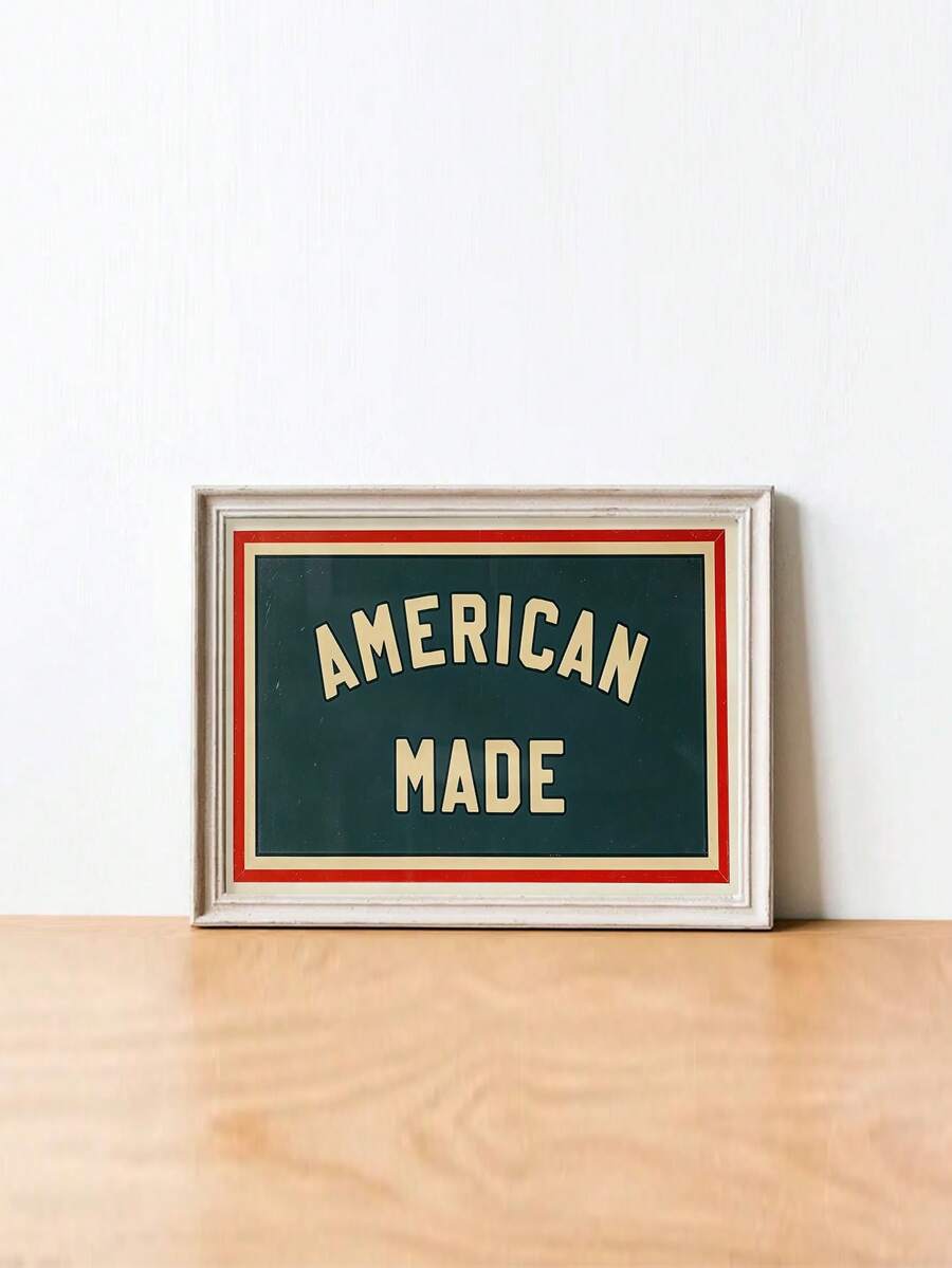 Cream framed AMERICAN MADE wall print resting on a pale wood tabletop