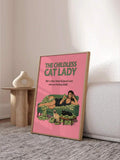 Framed pink cat lady poster leaning beside a wood pedestal