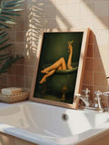 Framed forest-green figurative canvas poster displayed beside a sunlit bathtub with plants