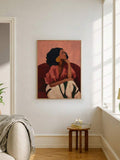 Pink clothing woman portrait canvas poster beside an armchair and wood table