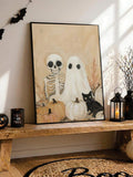 Black-framed Halloween ghost artwork beside a lantern, bats, and candle