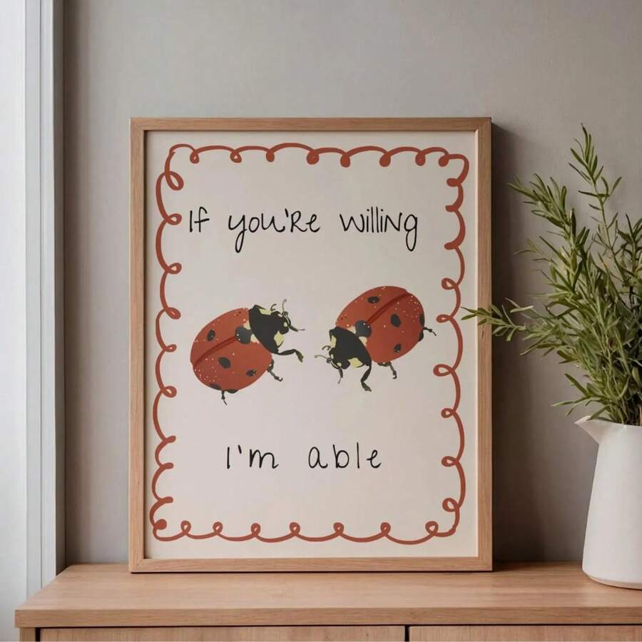 Oak-framed red ladybug print displayed on a cabinet with a white vase and leafy branches
