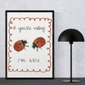 Straight-on view of black-framed retro ladybug poster beside a black dome lamp