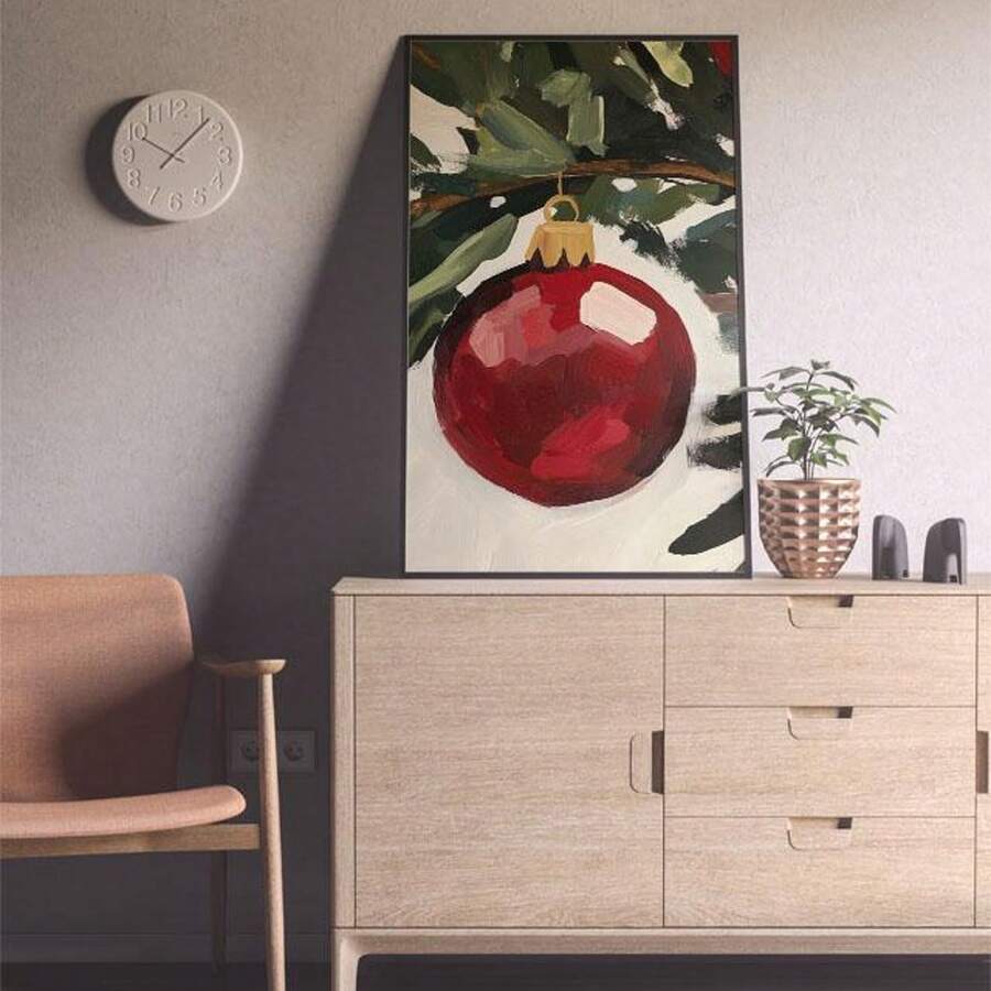 Single red bauble canvas displayed on a pale cabinet beside a chair and plant