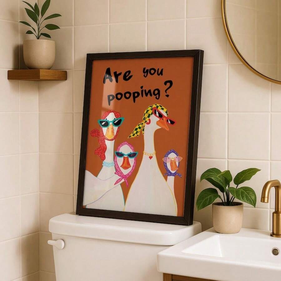 Funny goose typography wall art in a black frame above a toilet tank