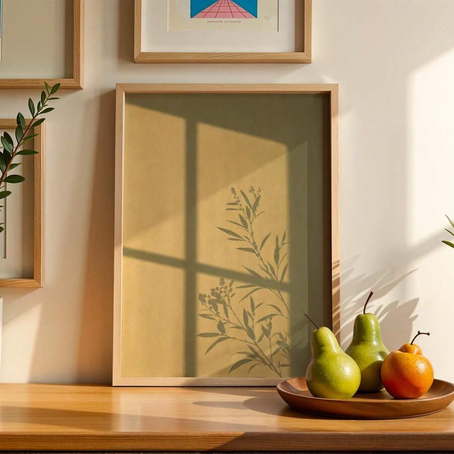 Framed olive botanical branch print with window shadows in a warm neutral interior