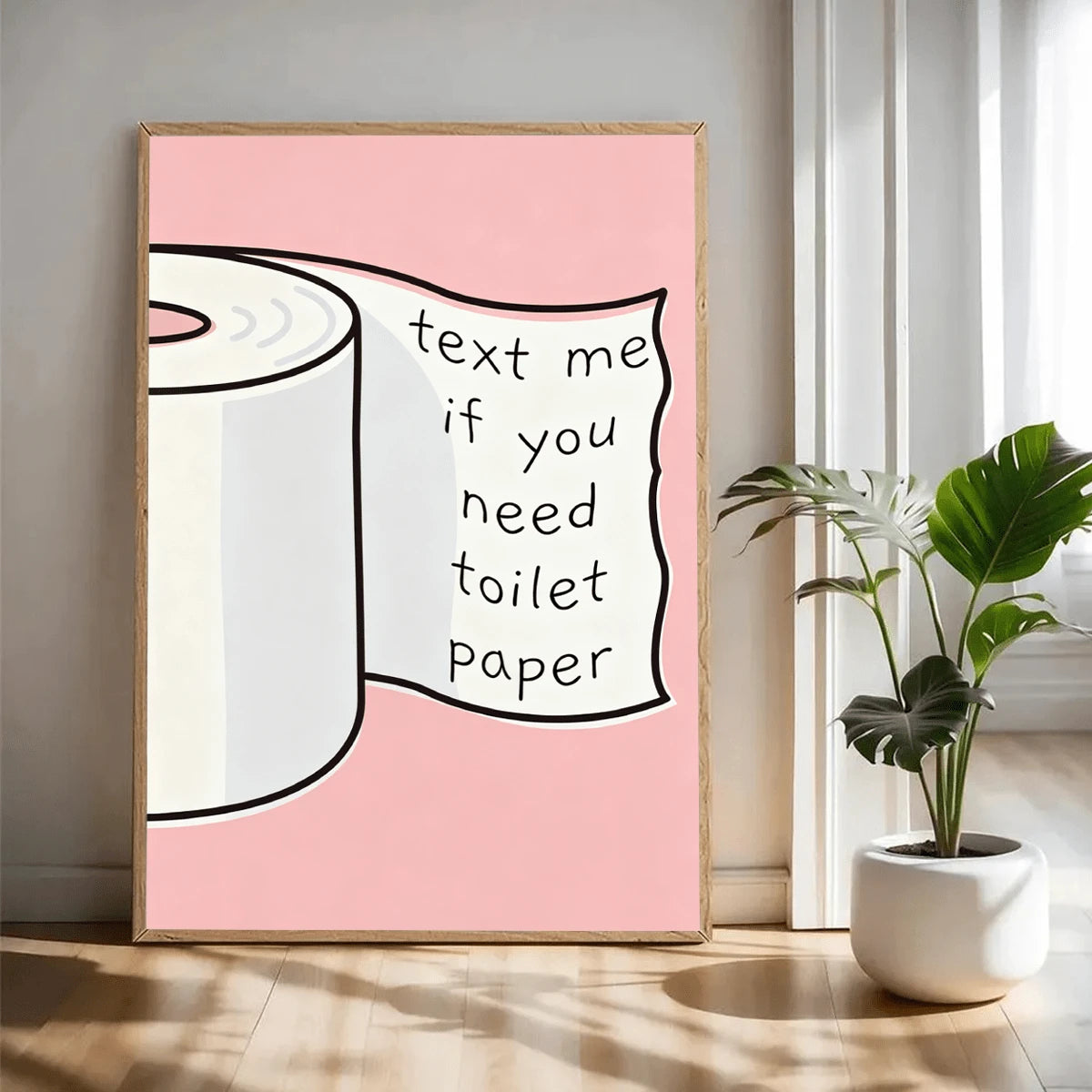 Playful bathroom quote art with black outlined toilet paper roll on blush pink