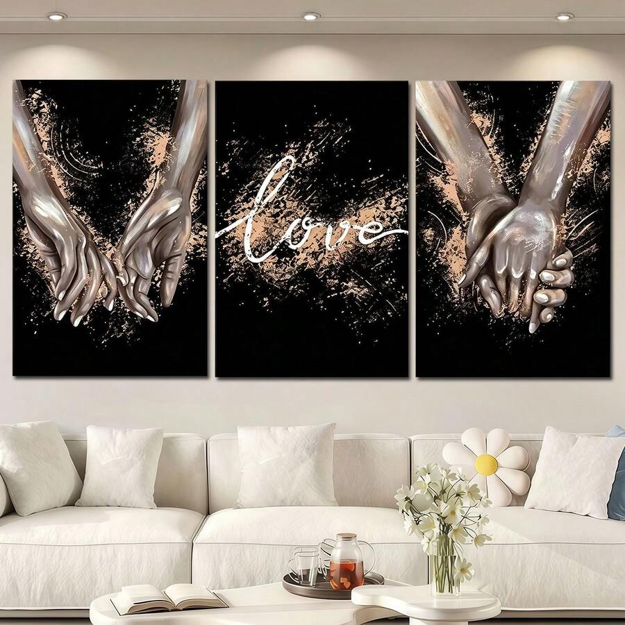Three black and gold love prints with reaching hands and script above a sofa
