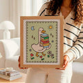 Person holding a framed goose-and-books illustration in a bright room