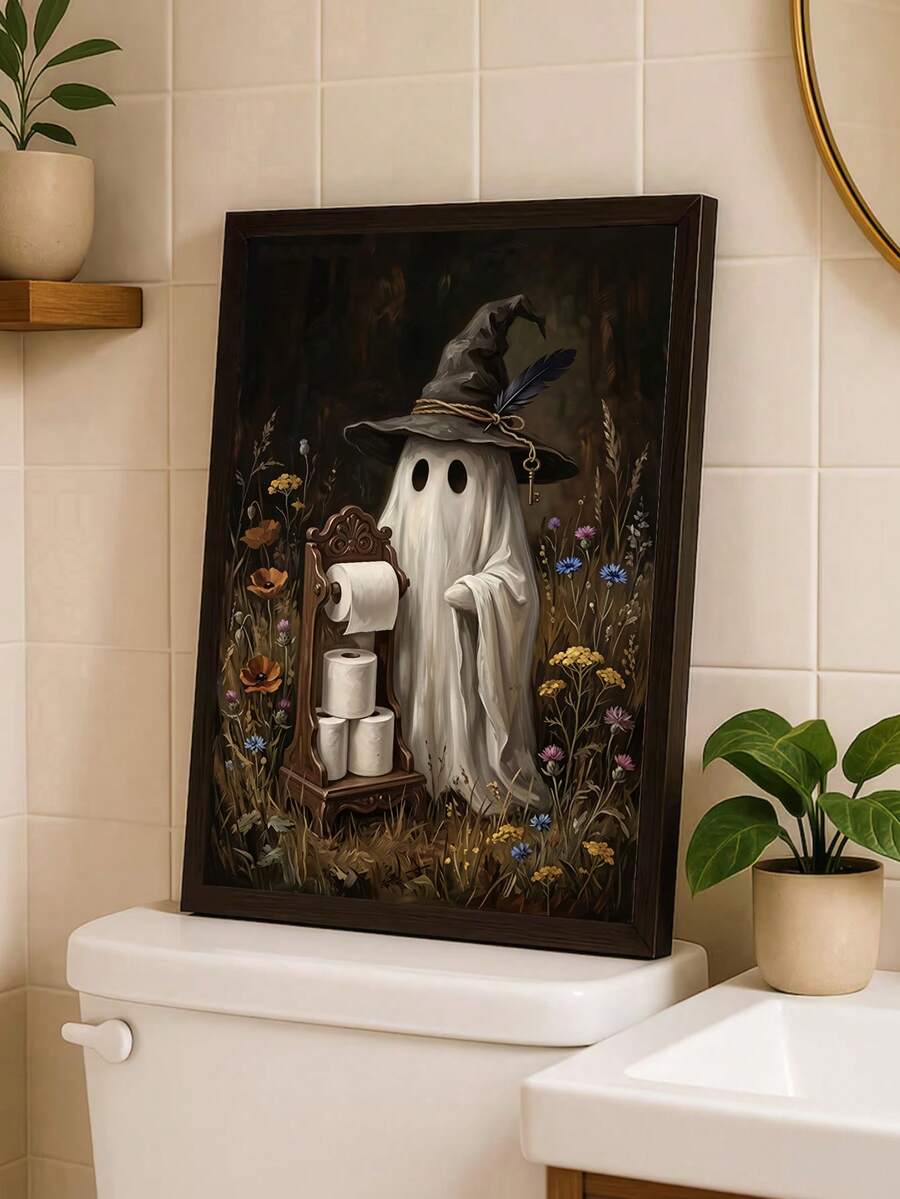 Framed witch hat ghost artwork styled on a bathroom toilet tank with a potted green plant