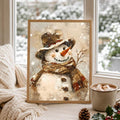 Framed snowman artwork on a window seat with a cream knitted blanket and mug overlooking snowy trees