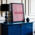 Pink dice canvas poster in a black frame on a blue sideboard