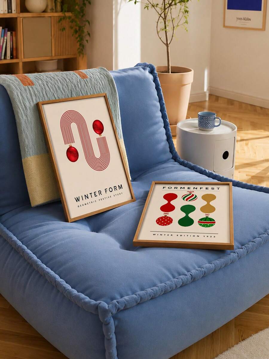 Two festive poster prints styled on a blue sofa in a sunlit room