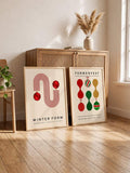 Mid-century ornament poster pair leaning beside a wood cabinet
