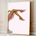 Oversized gold-framed pink martini poster leaning on the floor in a neutral paneled room