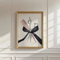 Scissors and pink comb watercolor artwork with a black ribbon bow in a gold-toned frame on a sunlit paneled wall
