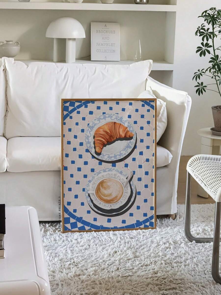 Croissant and coffee artwork displayed beside a kitchen sink and cabinets