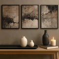 Three dark-framed neutral abstract posters above ceramic vases and candle