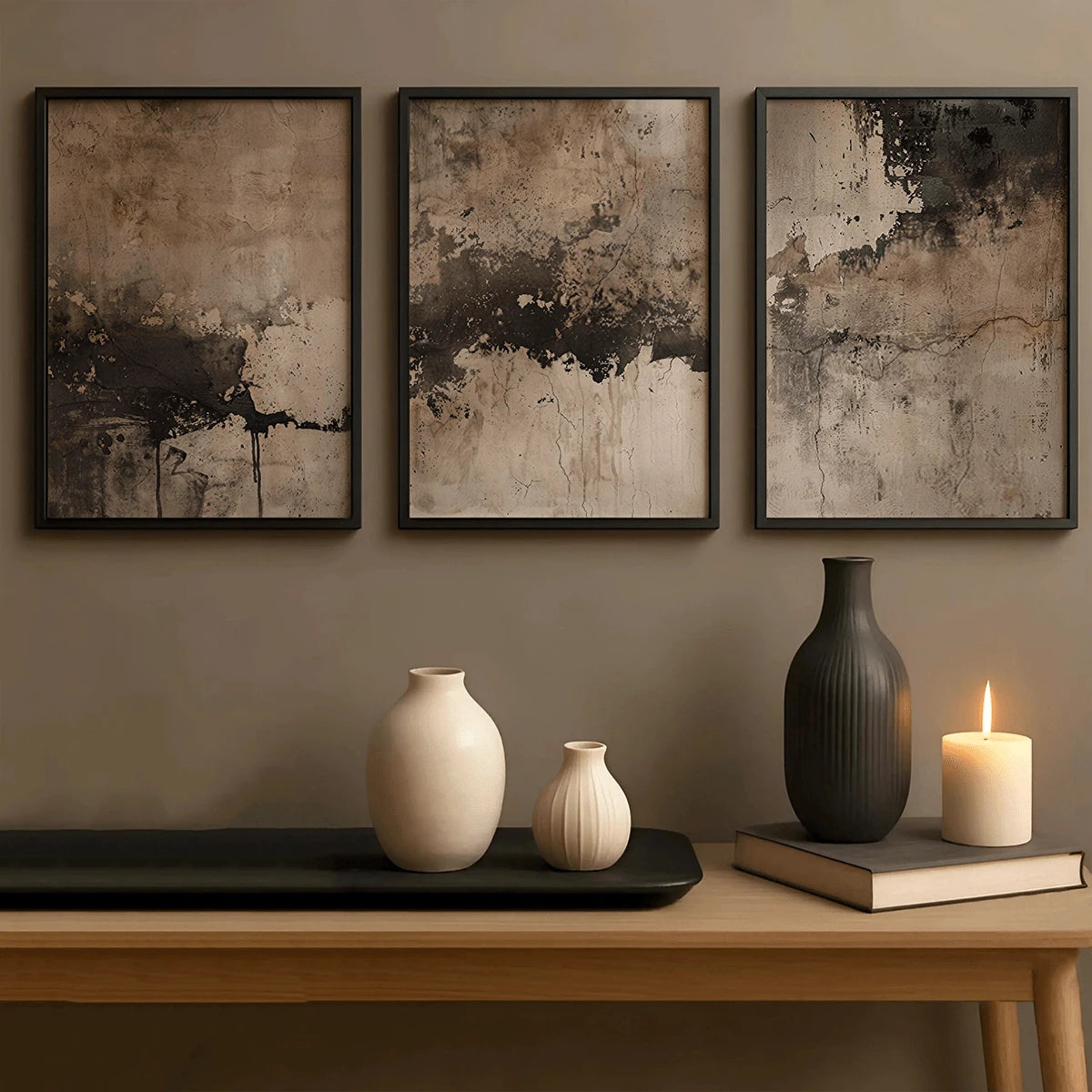 Three dark-framed neutral abstract posters above ceramic vases and candle