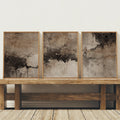 Neutral abstract three-piece wall art displayed on a rustic wood bench