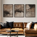 Wabi-sabi abstract canvas trio above a brown leather sofa