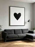 Framed black heart canvas centered above a charcoal sofa in a modern living room