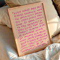 Pink handwritten quote canvas poster framed on a bed with neutral bedding