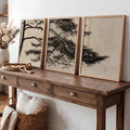 Pine branch triptych in natural wood frames displayed above a rustic console table