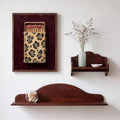 Framed leopard matchbox poster displayed above a vintage wood bench with a decorative vase