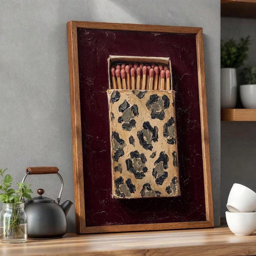Retro matchbox wall art in a wood frame styled beside a kettle and ceramics on a kitchen shelf