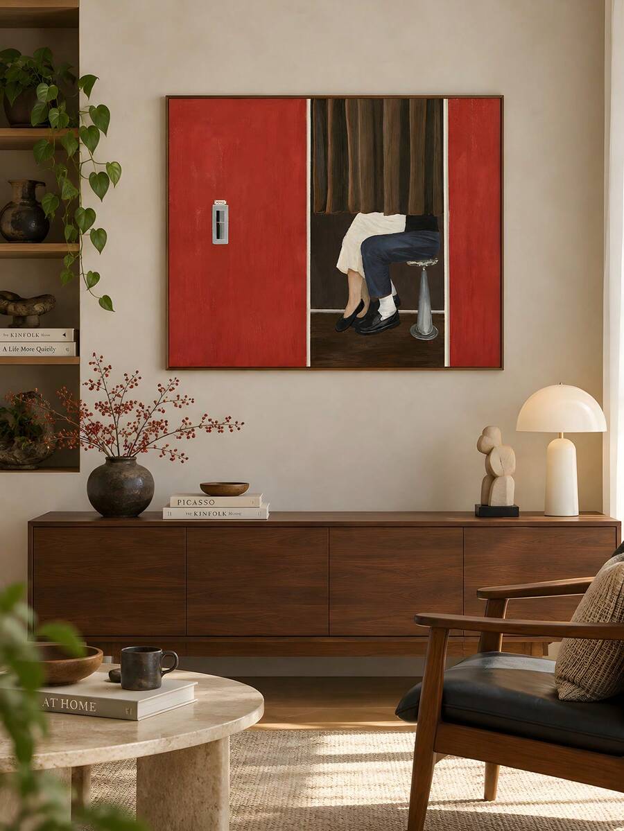 Wide framed figure artwork styled in a living room beside books and lamp