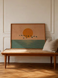 Boho coastal canvas wall art showing an orange sunset, calm sea, and dark birds across the horizon