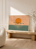 Walnut framed orange sun ocean artwork styled on a bench in a warm neutral room
