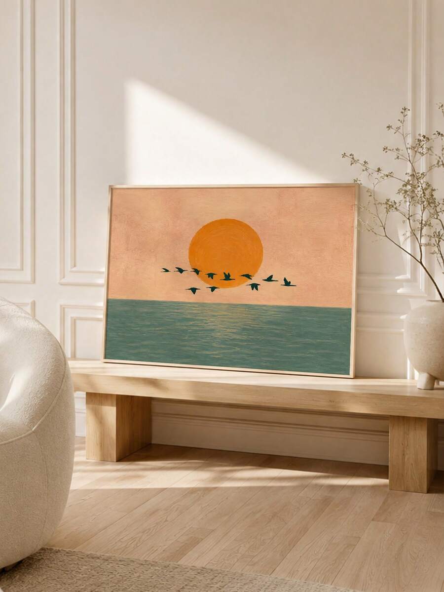 Walnut framed orange sun ocean artwork styled on a bench in a warm neutral room