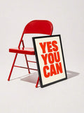 Red YES YOU CAN canvas poster displayed beside a bright red folding chair