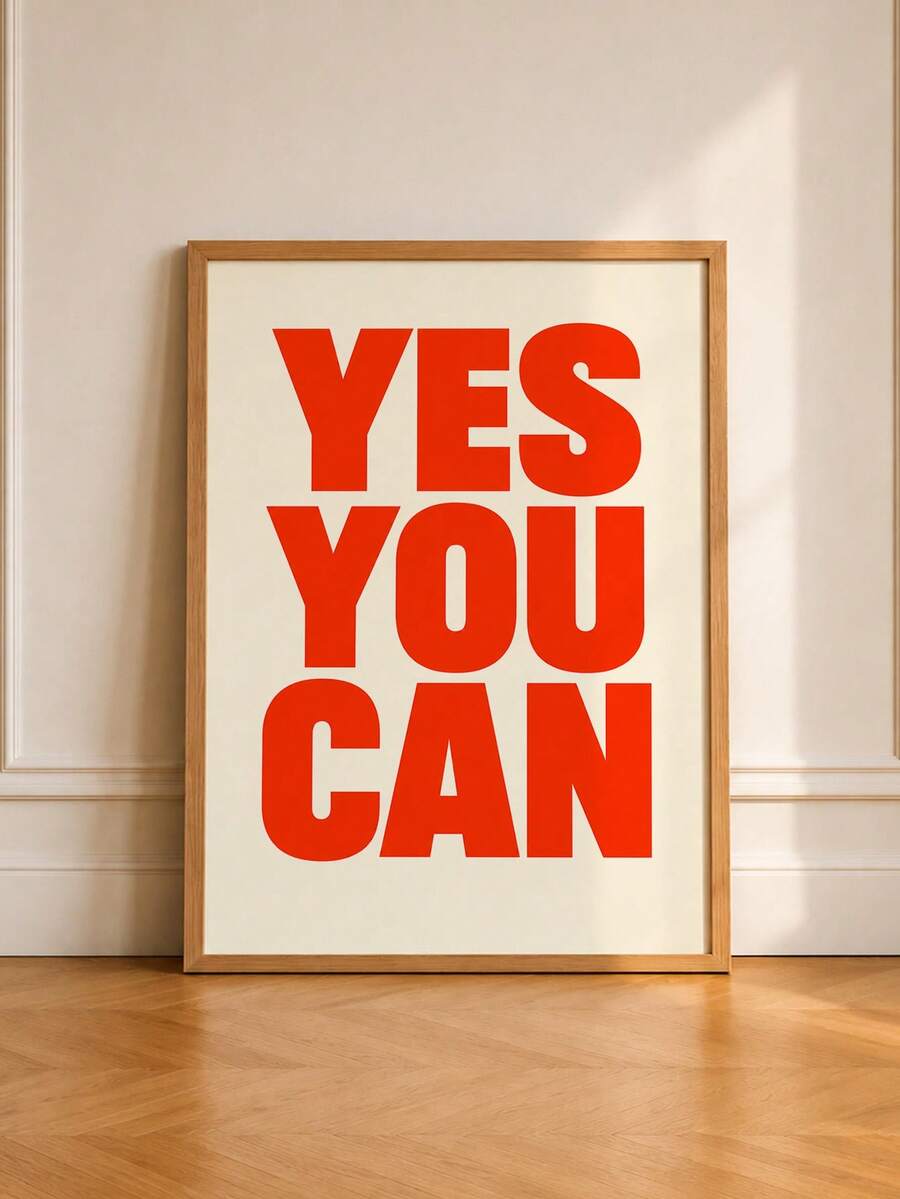 Wood-framed red YES YOU CAN typography print standing against a pale wall