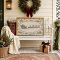 Framed Santa sleigh and reindeer artwork on a white porch bench beneath an evergreen wreath with a red bow