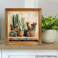 Wood-framed cactus print displayed beside a potted green plant on a shelf